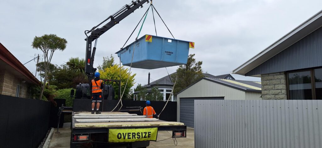 A Bermuda fibreglass pool being lifted into a customers back yard from a crane truck.