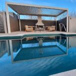 Modern backyard swimming pool with an elegant shaded lounge area and outdoor furniture, perfect for relaxing and entertaining in Bermuda.