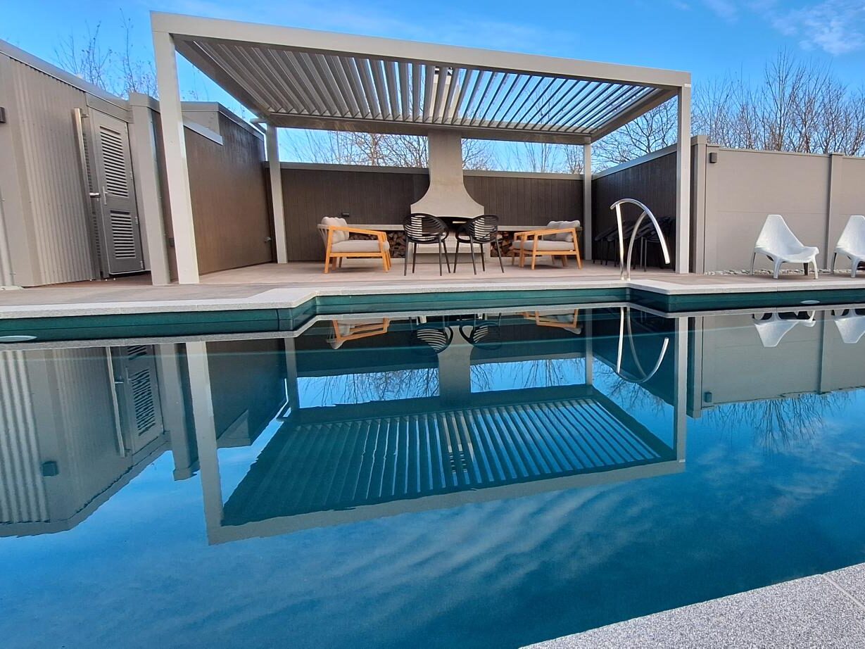 Modern backyard swimming pool with an elegant shaded lounge area and outdoor furniture, perfect for relaxing and entertaining in Bermuda.