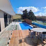 Modern Bermuda pool and outdoor living space with scenic countryside views, timber decking, glass fencing, and sleek pool design, perfect for relaxation and entertaining.