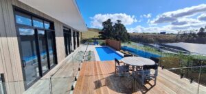 Modern Bermuda pool and outdoor living space with scenic countryside views, timber decking, glass fencing, and sleek pool design, perfect for relaxation and entertaining.