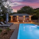 Stunning Bermuda pool with elegant lounge chairs and scenic sunset backdrop, perfect for relaxing and outdoor entertaining. High-quality pool installation and custom outdoor living design by Bermuda Pools.