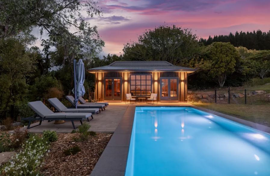 Stunning Bermuda pool with elegant lounge chairs and scenic sunset backdrop, perfect for relaxing and outdoor entertaining. High-quality pool installation and custom outdoor living design by Bermuda Pools.