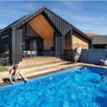 Modern residential swimming pool with outdoor deck and stylish house design in Bermuda. Perfect for family fun and relaxation, showcasing custom pool features and contemporary outdoor living space.