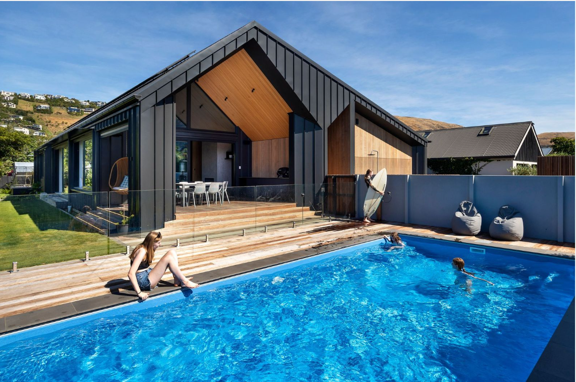 Modern residential swimming pool with outdoor deck and stylish house design in Bermuda. Perfect for family fun and relaxation, showcasing custom pool features and contemporary outdoor living space.