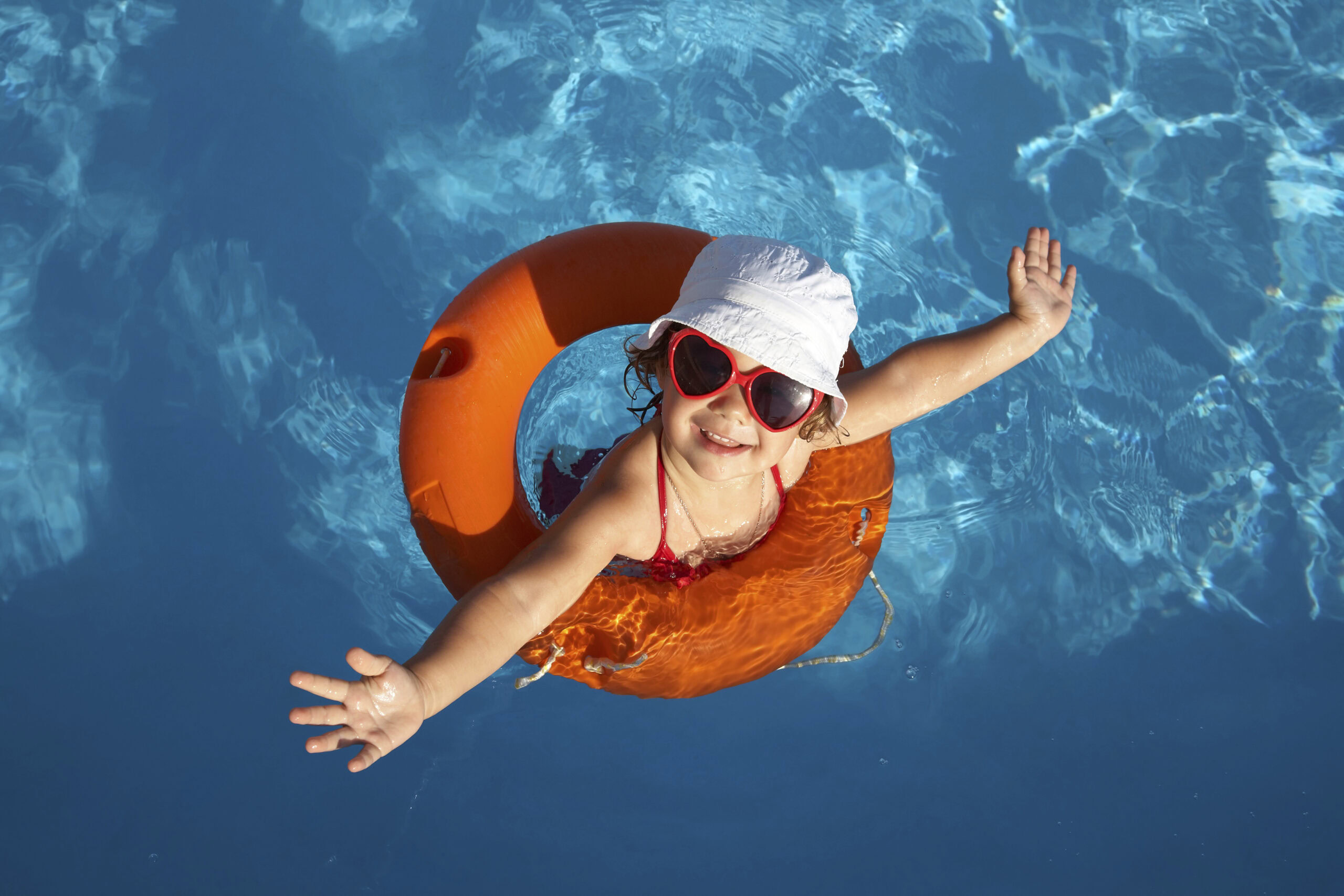 A young girl playing in a floatation ring in a back yard pool