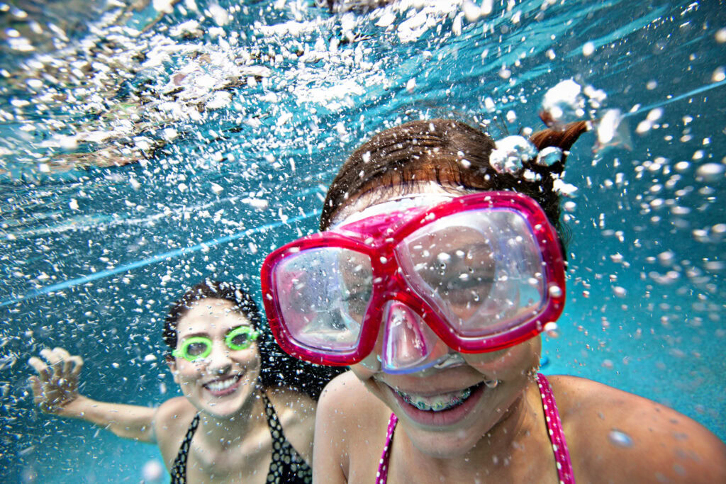 Bright smiling children enjoying swimming and snorkelling in a beautiful Bermuda pool, capturing fun and summer vibes at Bermuda Pools.