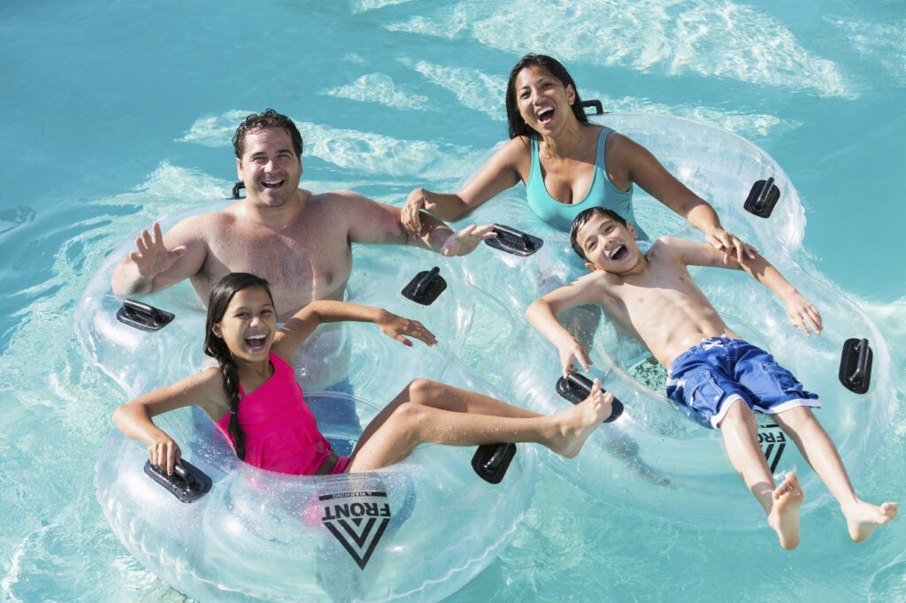 Vibrant family enjoying a fun day in a Bermuda Pool with inflatable tubes, clear blue water, and sunshine, perfect for relaxation and swimming.